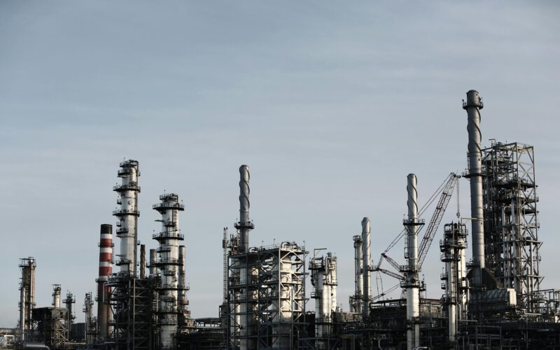 Skyline view of an industrial factory with tall chimneys against a clear sky.